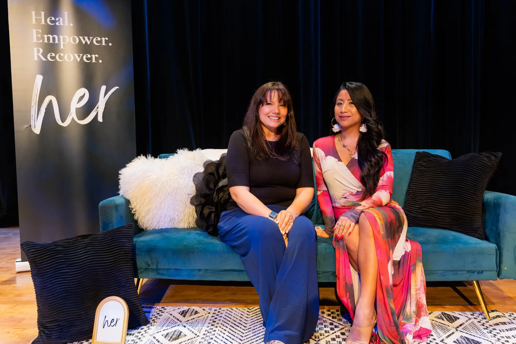 Brooke and a guest on the teal couch on stage at the HER. launch