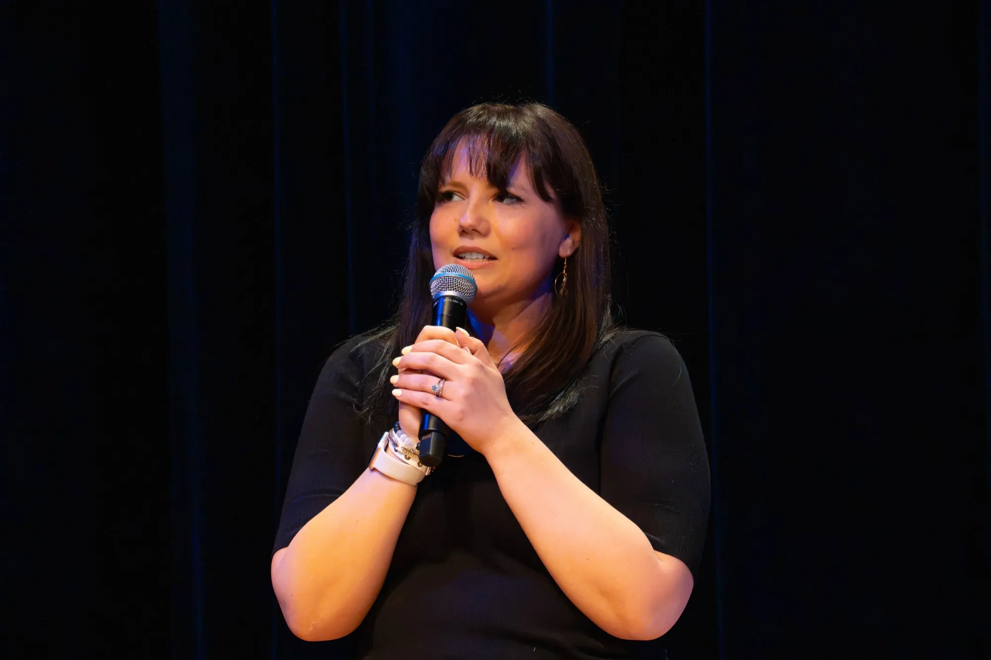 Brooke holding the microphone on stage, smiling